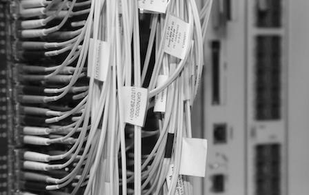 Black and white close-up image of fibre cables plugged into a machine