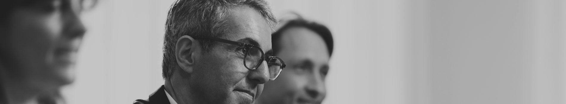 black and white image of two men and a woman in a professional setting, with focus on the man in the middle
